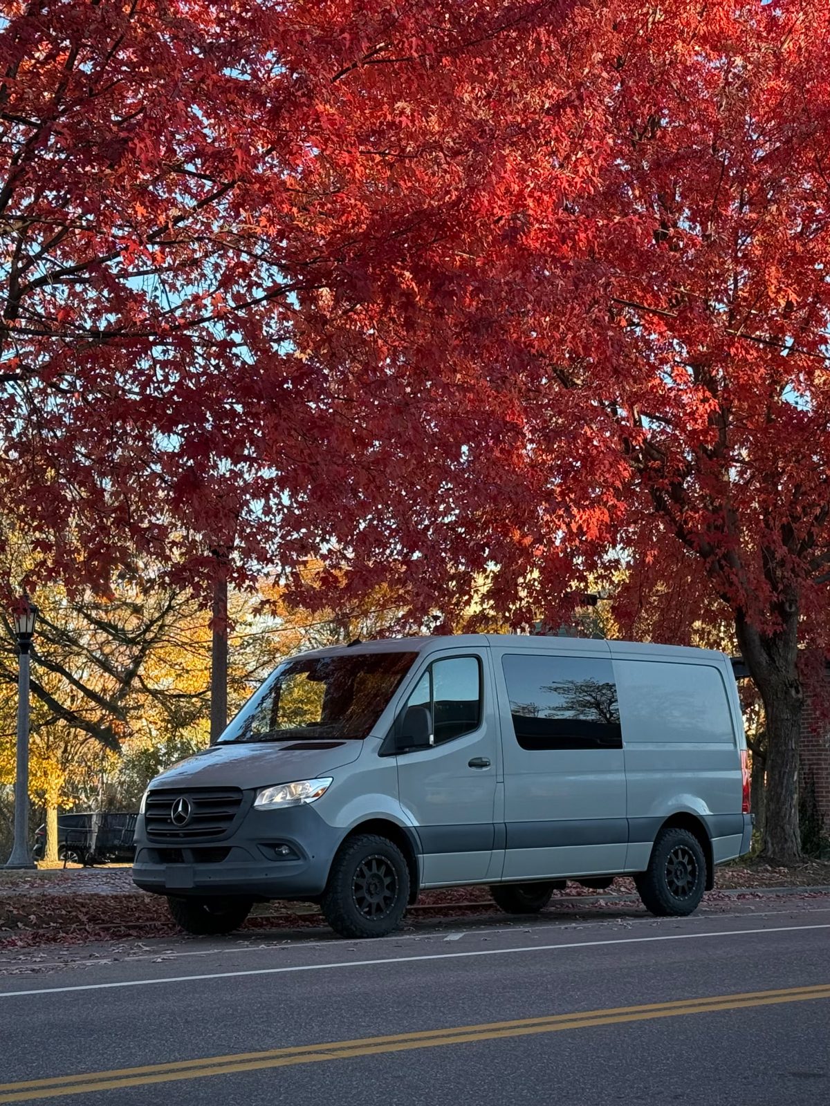 Mercedes-Benz Sprinter parked beneath red autumn maple trees